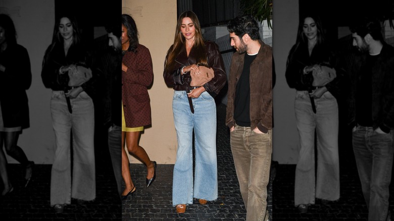 Sofía Vergara in Los Angeles in March 2025 wearing a brown leather jacket, heels, blue jeans, and carrying a tan YSL clutch bag