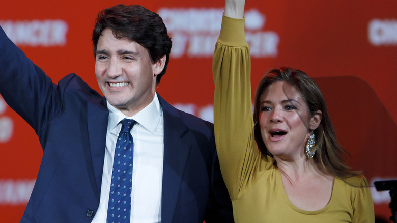 Justin Trudeau and Sophie Grégoire smiling and raising their respective right arms