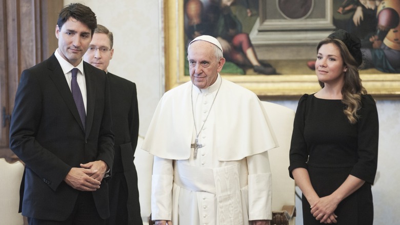 Pope Francis in a white robe standing between Sophie Gregoire Trudeau and Justin Trudeau.