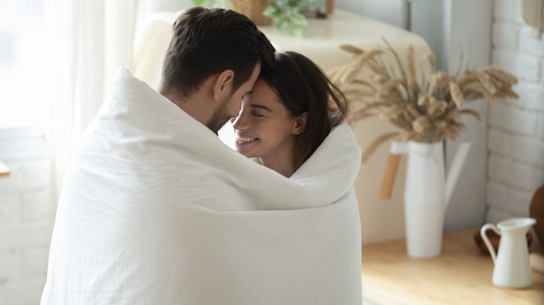 Couple cuddled up together in a white blanket