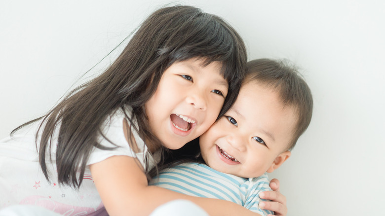 Baby girl hugging sibling