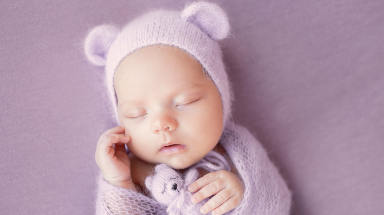 Baby sleeping, holding teddy bear