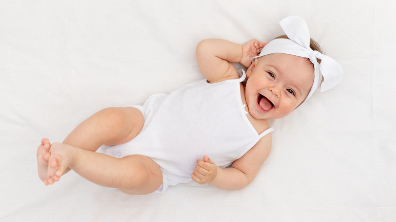 Baby girl dressed in white, laughing