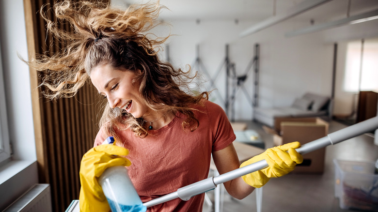 Woman happy and dancing with mop