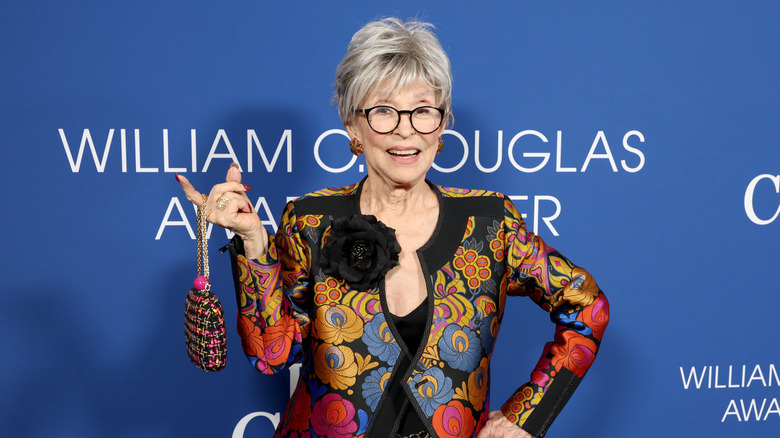 Rita Moreno displaying her purse on a red carpet