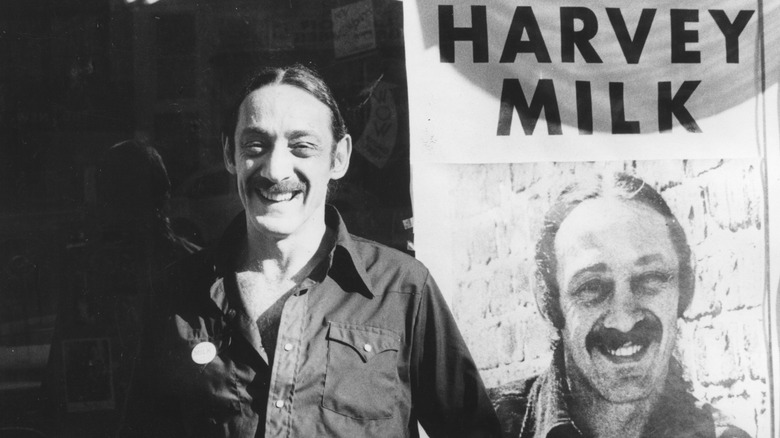 Harvey Milk in front of a 1973 campaign image