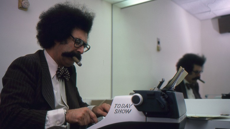 Gene Shalit smoking a cigar while typing on a typewriter