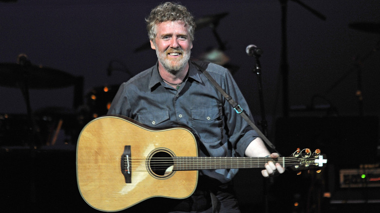 Glen Hansard smiling, holding his guitar