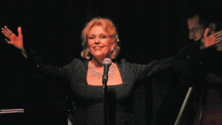 Eileen Fulton performing onstage in a black dress with her arms raised
