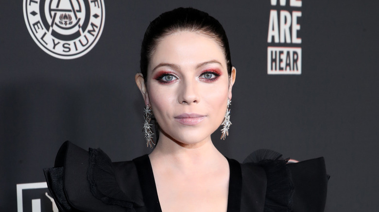 MIchelle Tractenberg posing on a red carpet in front of a dark gray background