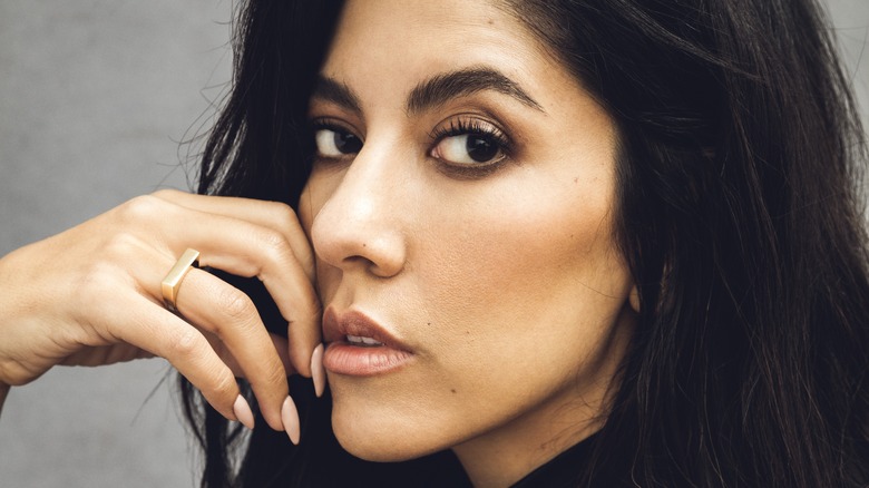 Stephanie Beatriz with her hand on her cheek