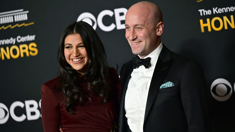 Katie Miller smiling while posing next to Stephen Miller at a glitzy event