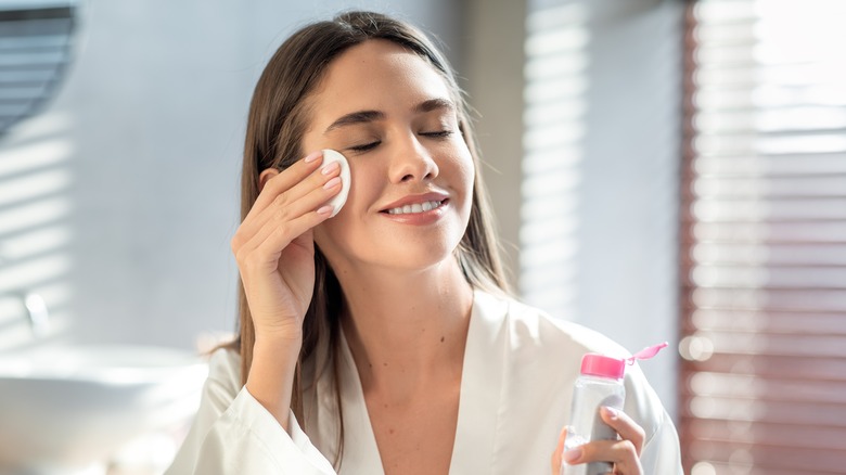 Woman removing makeup with a makeup pad