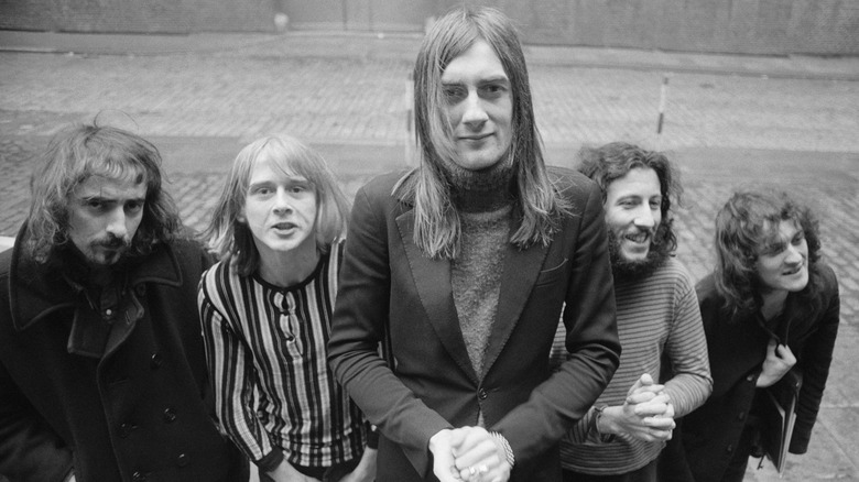 Mick Fleetwood looking serious as he stands in front of his bandmates, with Peter Green smiling to his right