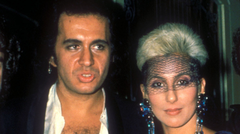 Cher wearing a face net and posing with Gene Simmons