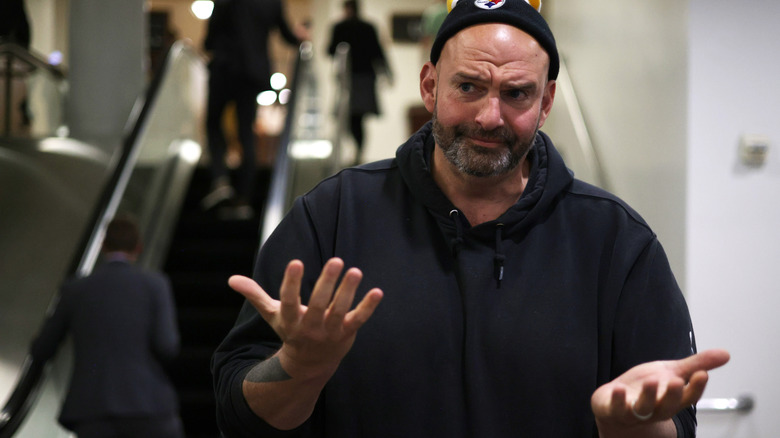 John Fetterman in a hoodie and beanie, his hands opened and facing up.