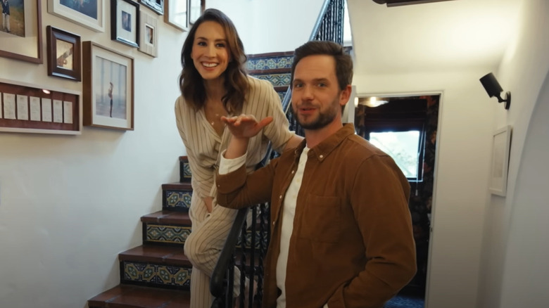 Troian Bellisario standing on stairs and laughing beside Patrick J. Adams