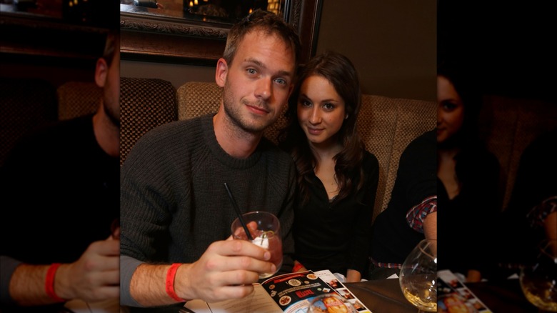 Patrick J. Adams and Troian Bellisario seated at a table with drinks