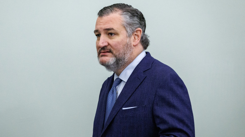 Ted Cruz walking and grimacing in a navy suit