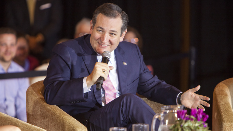 Beardless Ted Cruz speaking into a microphone in a suit