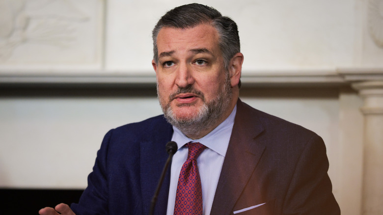 Ted Cruz looking confused in front of a microphone in a suit
