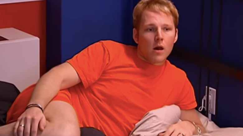 Kayne Gillaspie in an orange outfit while resting in bed during "Project Runway" season three