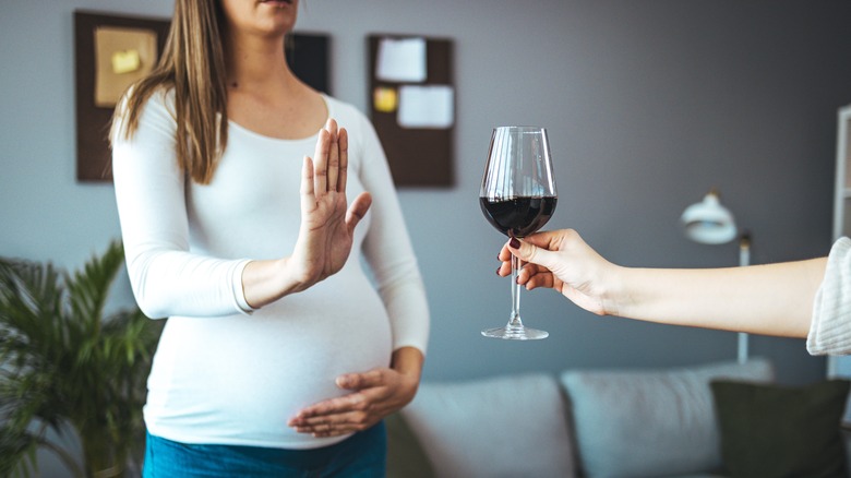 pregnant woman declining a glass of wine