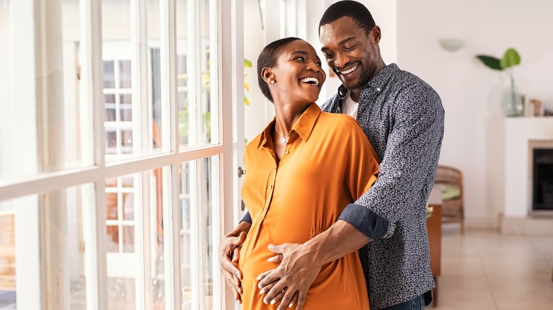 smiling man embracing pregnant partner