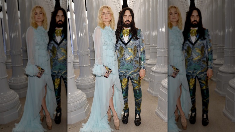 Brie Larson posing with a long-haired, bearded man in a blue tiger-print suit