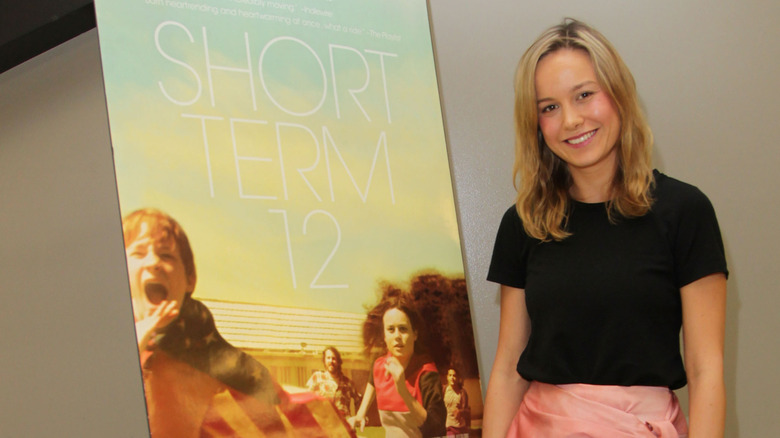 Brie Larson posing beside a poster for Short Term 12