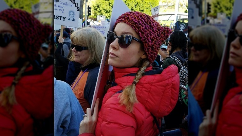 Brie Larson marching in a protest with a sign