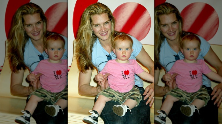 Brooke Shields smiles sitting down holding her daughter Rowan Henchy as a baby
