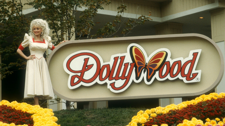 Dolly Parton posing next to Dollywood sign