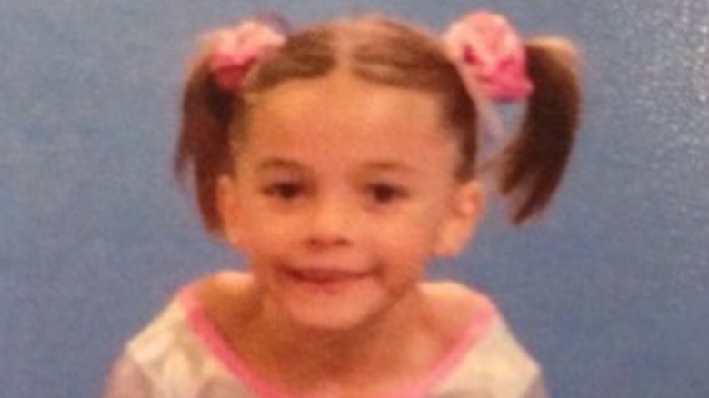 Olivia Dunne smiling as a child in pigtails and gymnast leotard