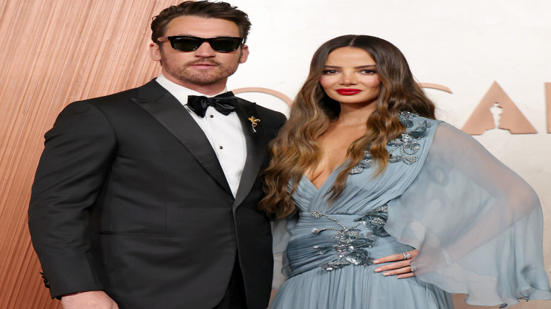 Miles Teller and Keleigh Sperry posing on the 2025 Oscars step-and-repeat