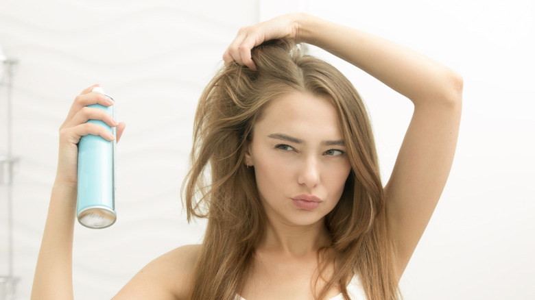 A woman putting on hair spray 