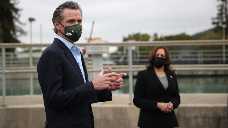 Gavin Newsom speaking with Kamala Harris in the background