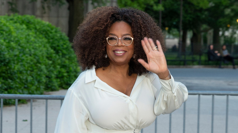 Oprah Winfrey (wearing white) waving as she walks in 2019.