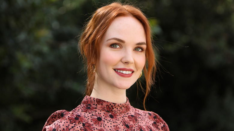 Morgan Kohan smiling outside wearing a red floral dress.