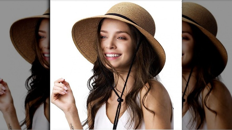 woman wearing medium-length brim straw sun hat with thin black ribbon
