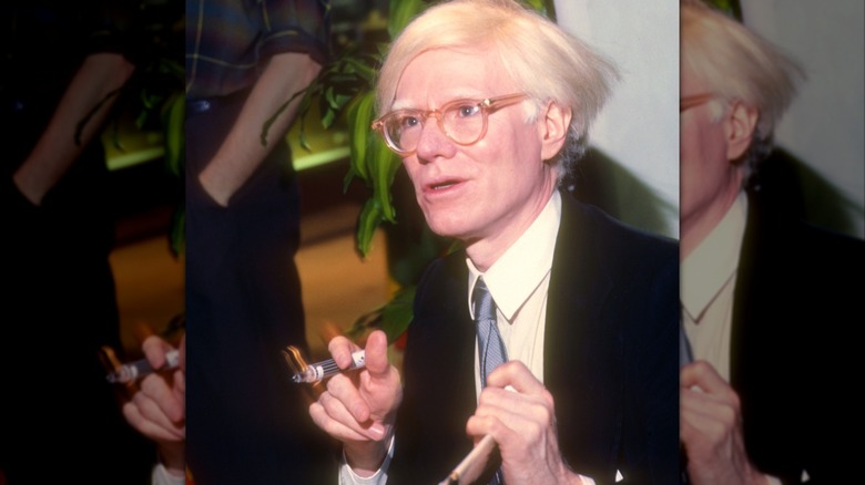 Andy Warhol holding a marker as if he's about to draw