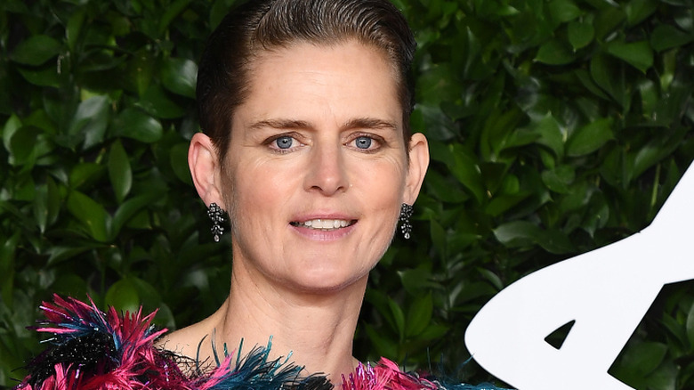 Stella Tennant smiling with a slickback pixie and ruffled outfit