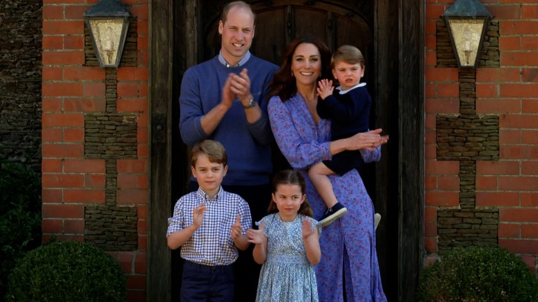 Prince William, Kate Middleton and kids George, Charlotte and Louis clapping and smiling.
