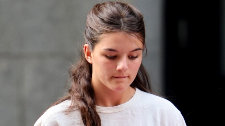 Suri Cruise looking down in white t-shirt