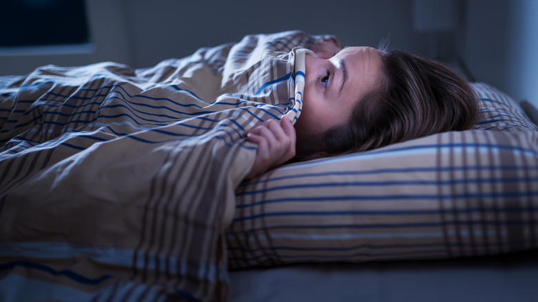 Frightened person hiding under blanket