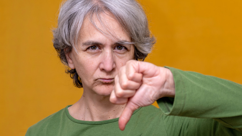 A woman frowning and holding thumb down