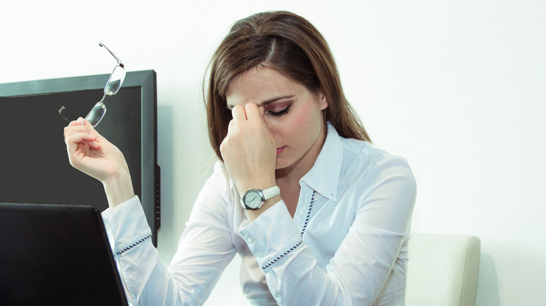 Woman holding her glasses while looking tense