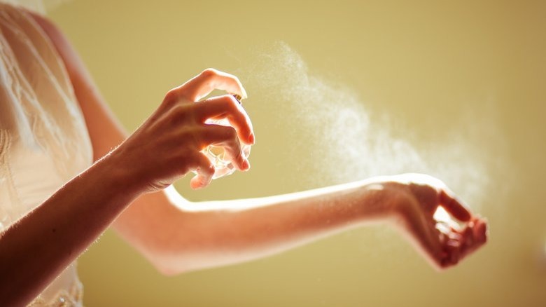 A woman spraying perfume on her arm