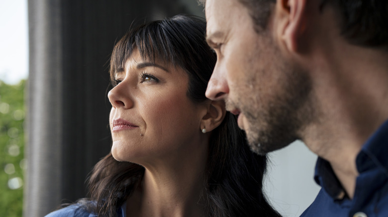 Woman looks out of window, away from man