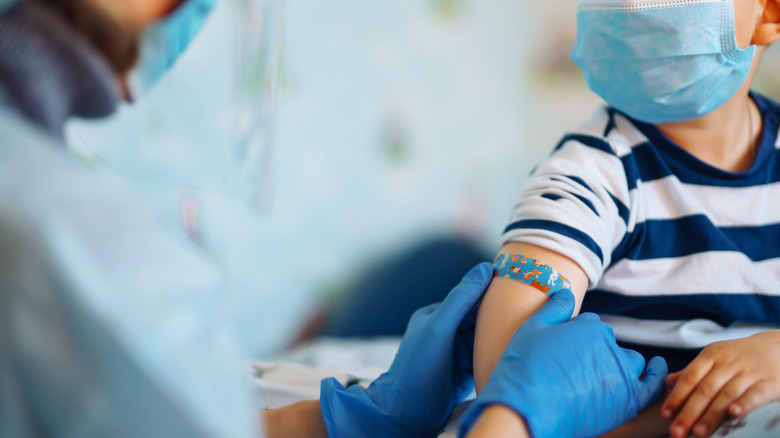 Children's doctor vaccinating little boy at home.